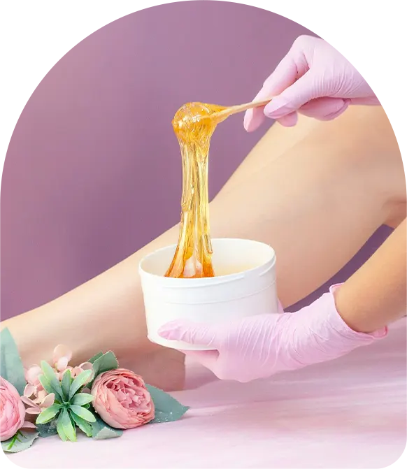 Young woman having hair removal procedure on leg with sugaring paste in salon